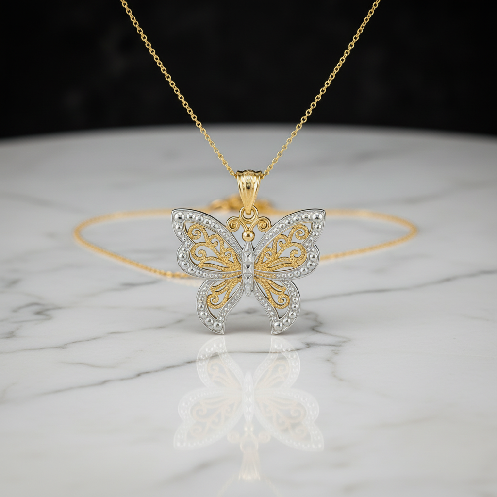 A gold and silver butterfly pendant necklace with clear rhinestone accents, displayed on a white marble surface with a black background.