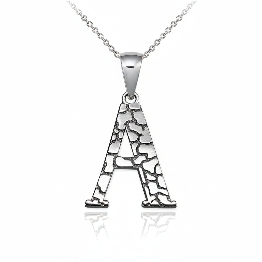 A silver pendant necklace featuring the letter 'A' with a textured, crackled pattern, suspended from a delicate silver chain on a white background with a soft reflection.