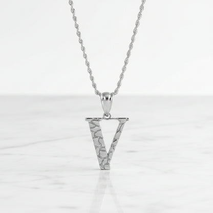 Silver letter V pendant necklace with a textured, openwork design on a matching chain, shown on a white background with a soft reflection.