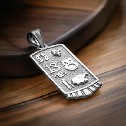 A sterling silver lucky charm pendant with multiple good luck symbols such as a horseshoe, lucky 13, shamrock, owl, and white elephant, displayed on a wooden surface.