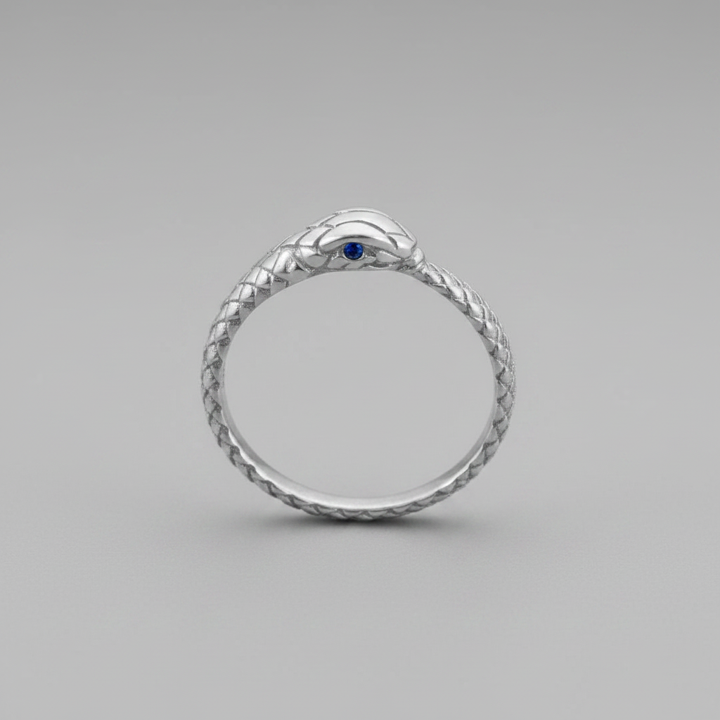 A silver snake ring with a textured scale pattern and a small blue gemstone in the center of the head, shown on a neutral gray background.