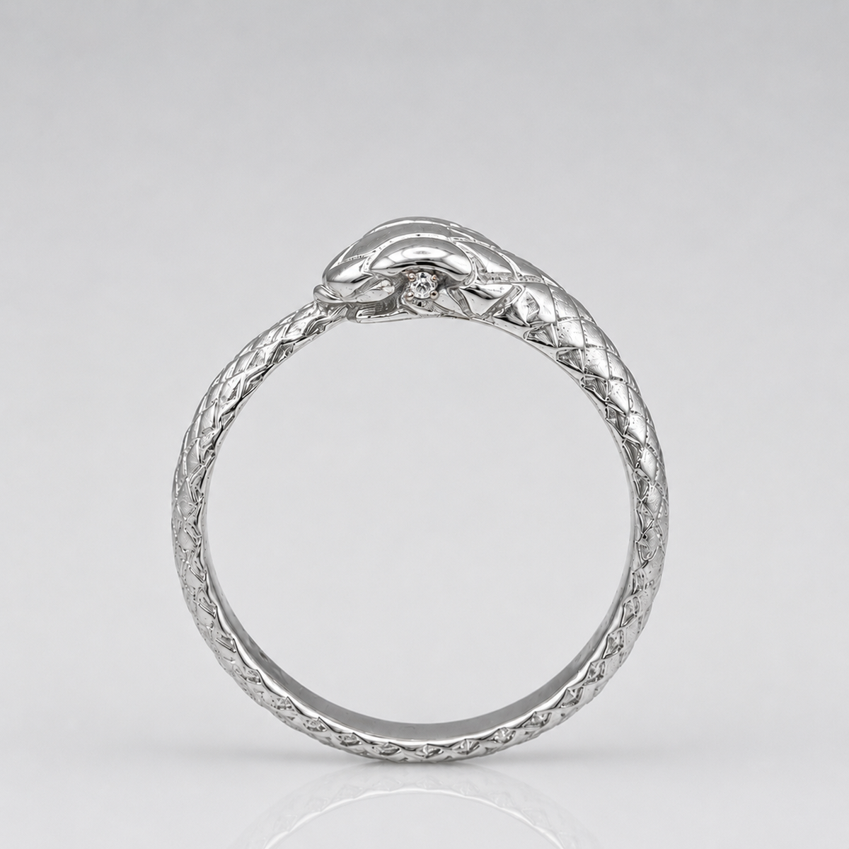 A silver snake ring with a textured, braided band and a polished snake head at the top, set against a light gray background.
