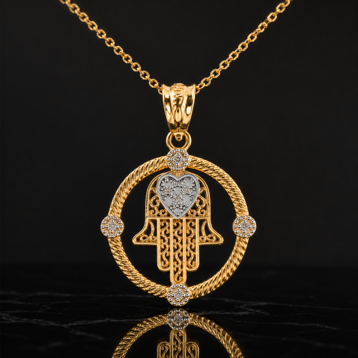 A gold Hamsa hand pendant necklace with a heart-shaped center, accented with small clear stones, shown on a black reflective background.