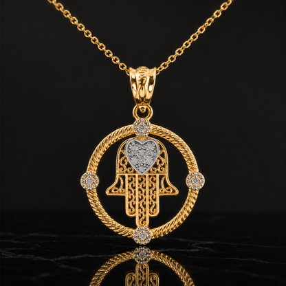 A gold Hamsa hand pendant necklace with a heart-shaped center, accented with small clear stones, shown on a black reflective background.