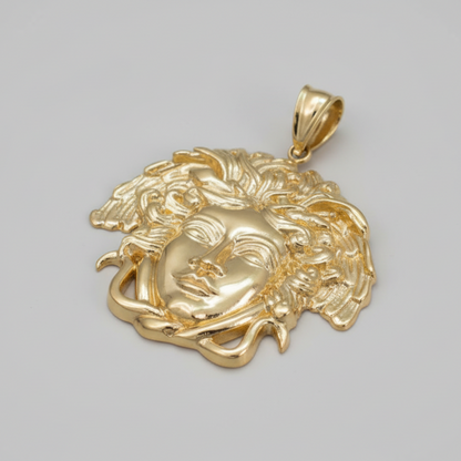 Gold pendant with intricate design on a gray background