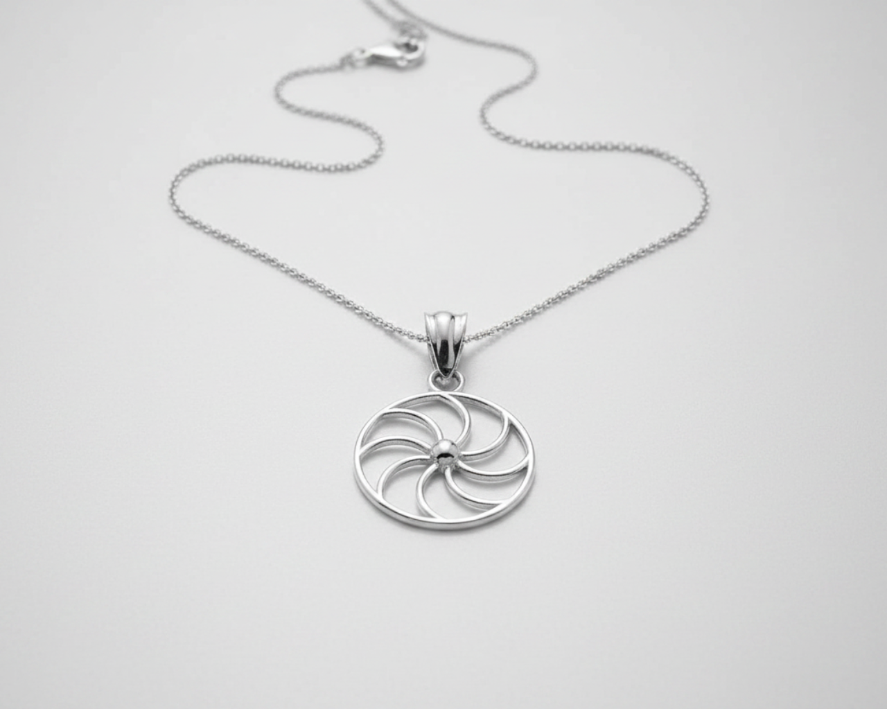Silver circular pendant necklace on a white background