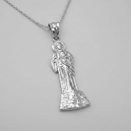A sterling silver pendant necklace featuring a detailed figure of the Virgin Mary holding the infant Jesus, suspended from a matching silver chain against a neutral gray background.
