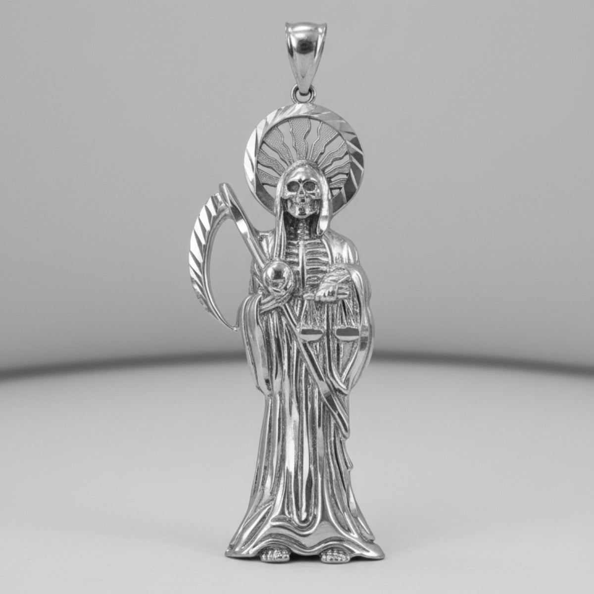 Silver pendant of a Santa Muerte religious figure with a halo on a white background