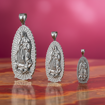 Three silver religious pendants on a reflective surface with a pinkish-purple gradient background