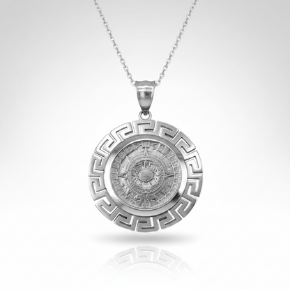 A silver pendant necklace featuring a circular Greek key border and a detailed central compass design, suspended from a fine silver chain against a light gray gradient background.