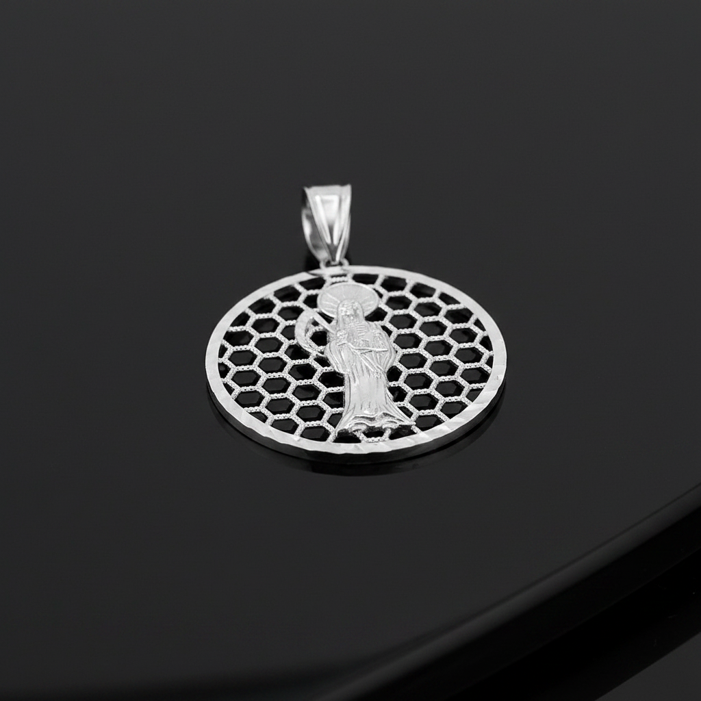 A silver pendant featuring a detailed figure of Santa Muerte set against a honeycomb circular pattern, displayed on a glossy black surface.
