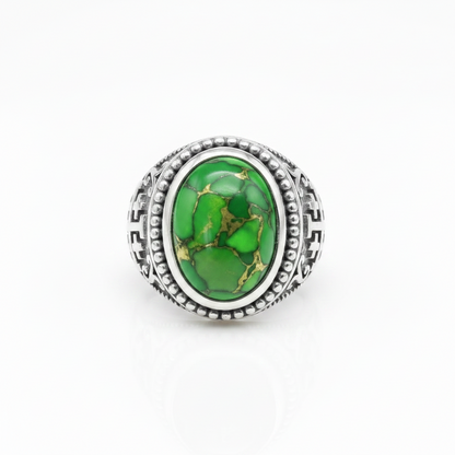 A silver-toned ring featuring an oval green stone with natural gold and darker green veining, set in a detailed textured bezel on a white background.
