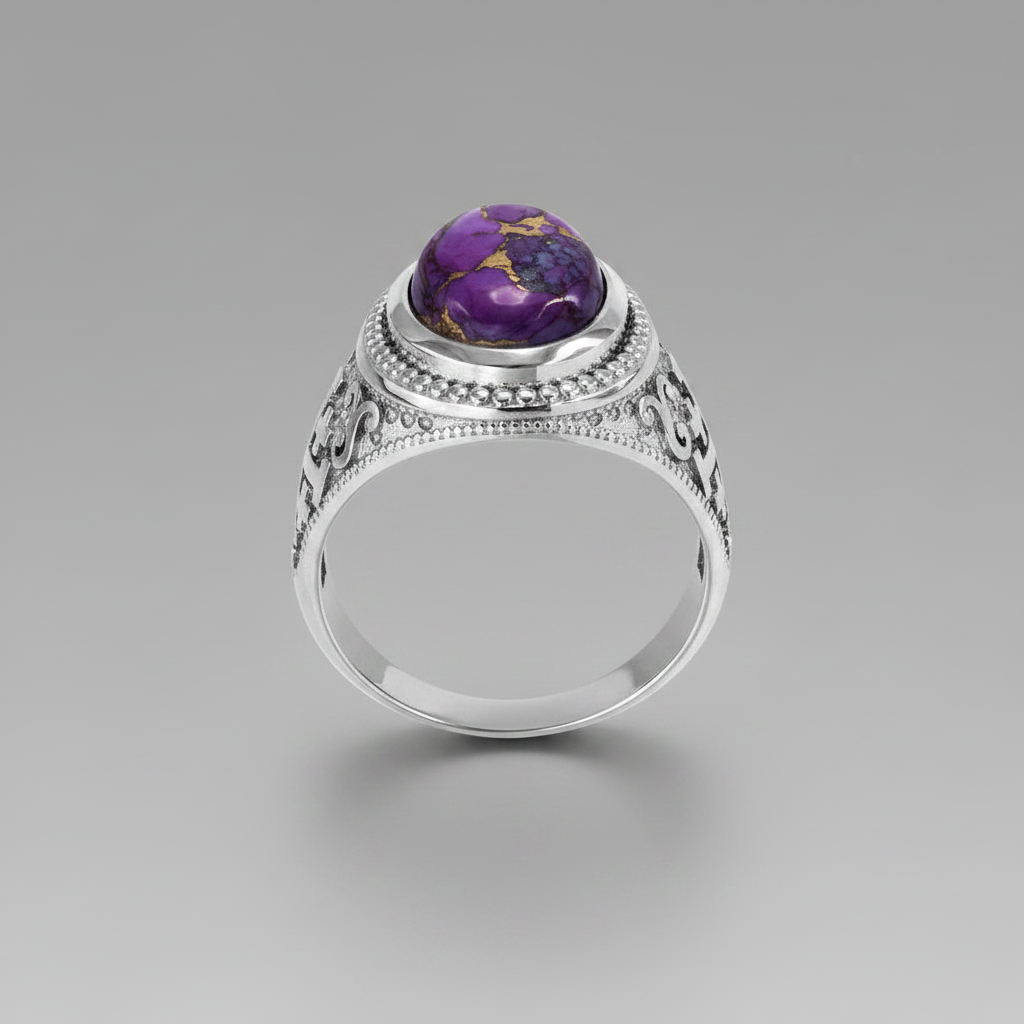 A silver ring with an ornate filigree band and a round purple gemstone featuring gold inclusions, shown on a neutral gray background.
