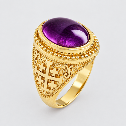 A gold signet ring featuring a large oval purple amethyst cabochon stone, with an ornate filigree cross motif on the front of the shank, set against a clean light gray background.
