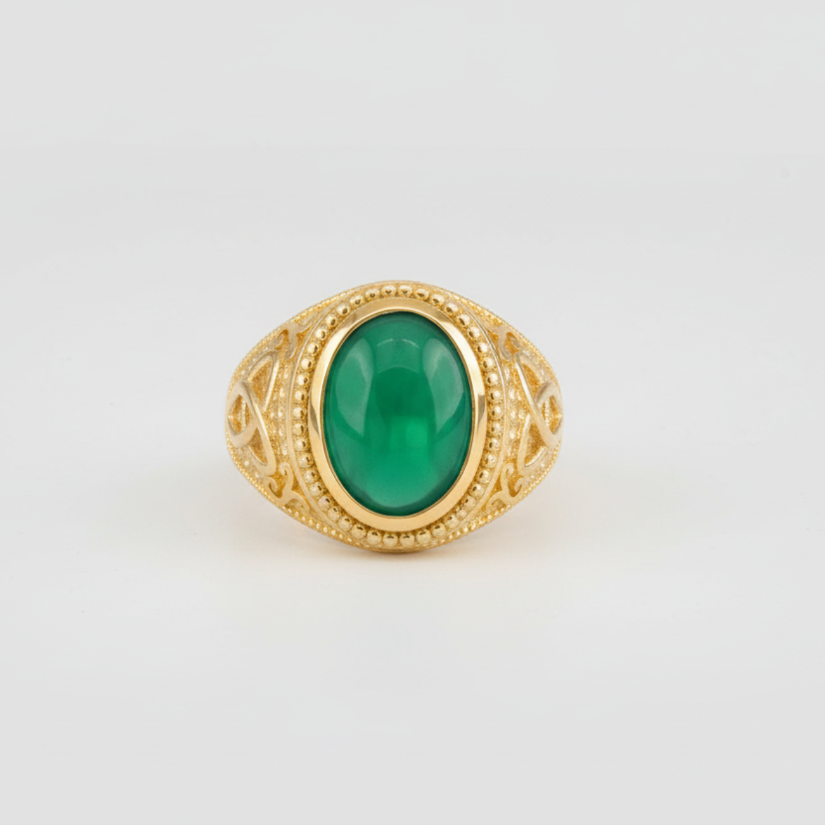 Gold ring with a green gemstone on a light gray background