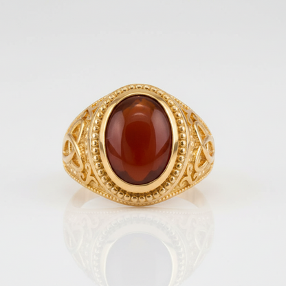 Gold ring with a red stone on a white background