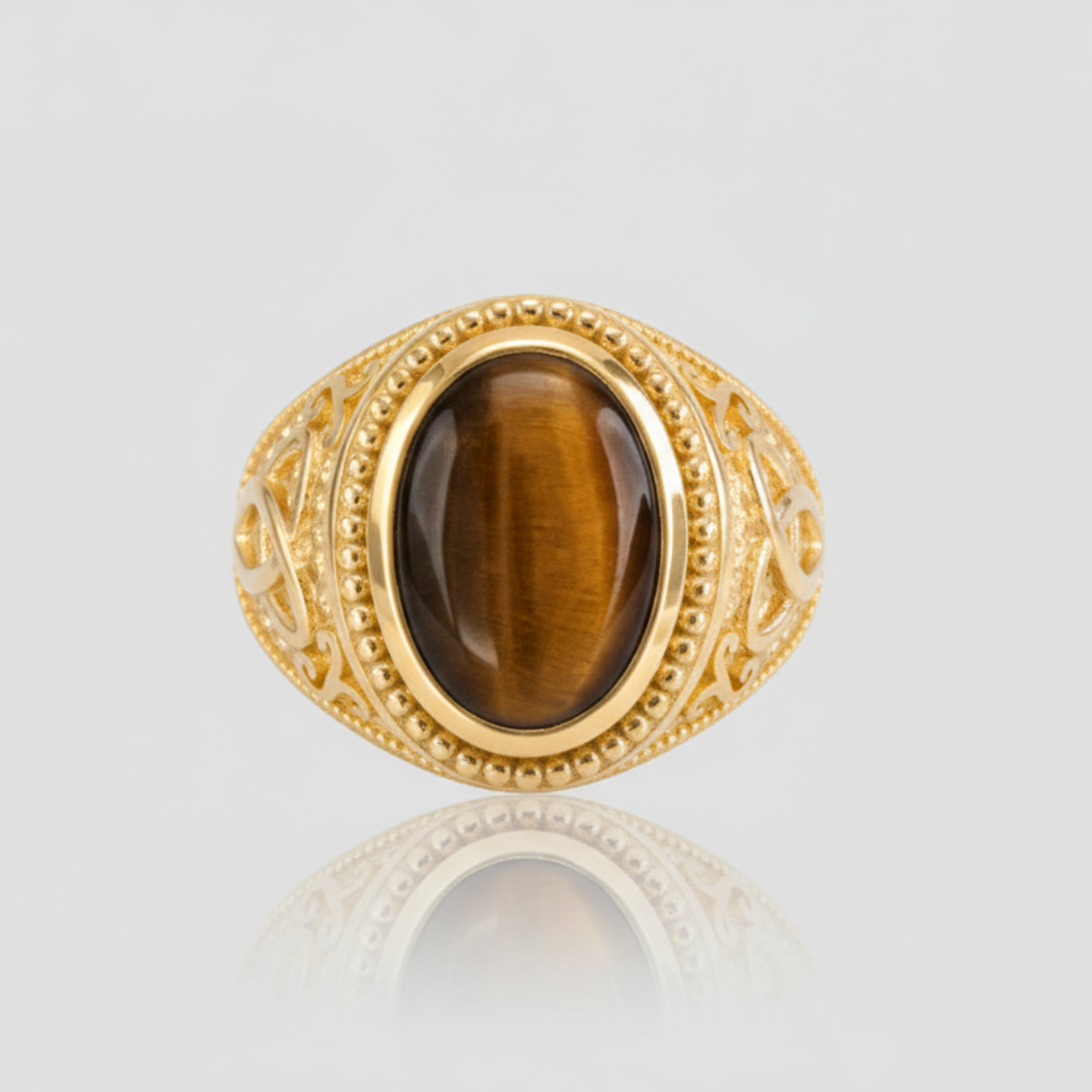 Gold ring with a brown gemstone on a light gray background