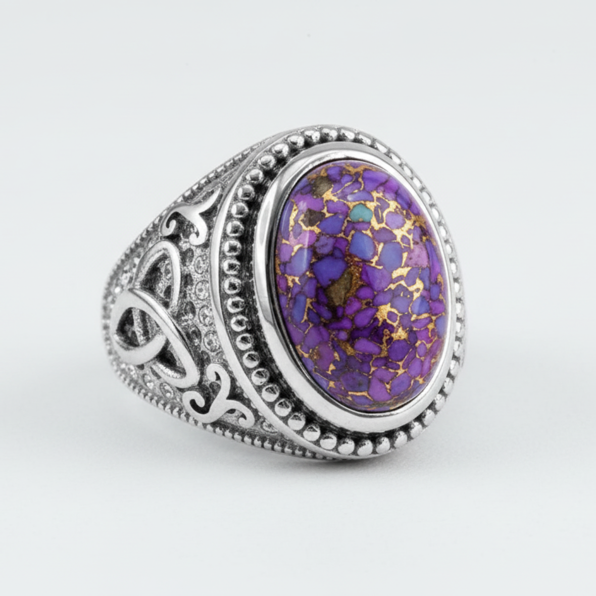 Ring with purple and gold speckled stone on a white background