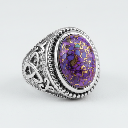 Ring with purple and gold speckled stone on a white background