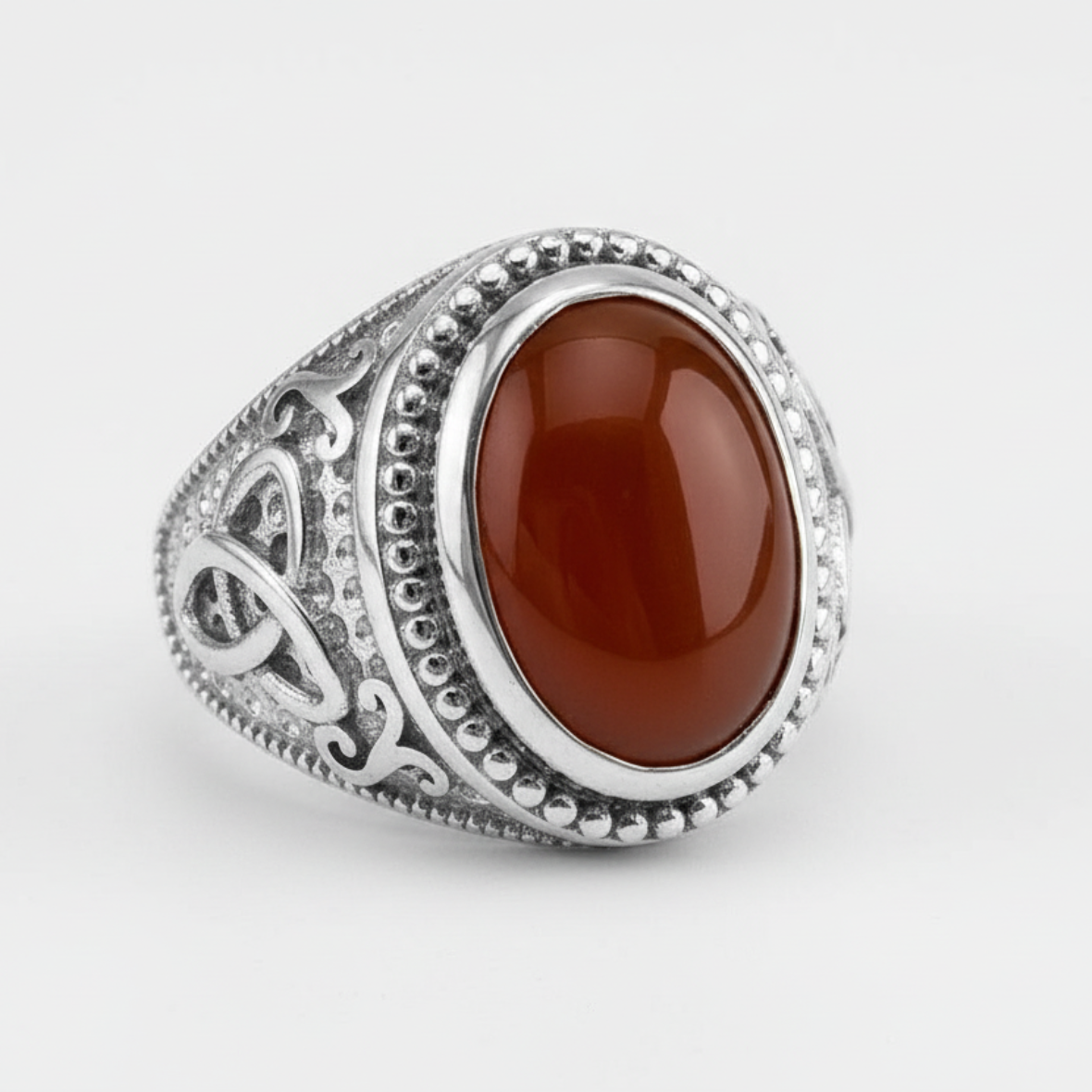 Silver ring with a red stone on a white background