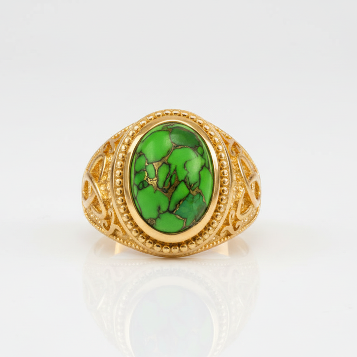Gold ring with a green stone on a white background