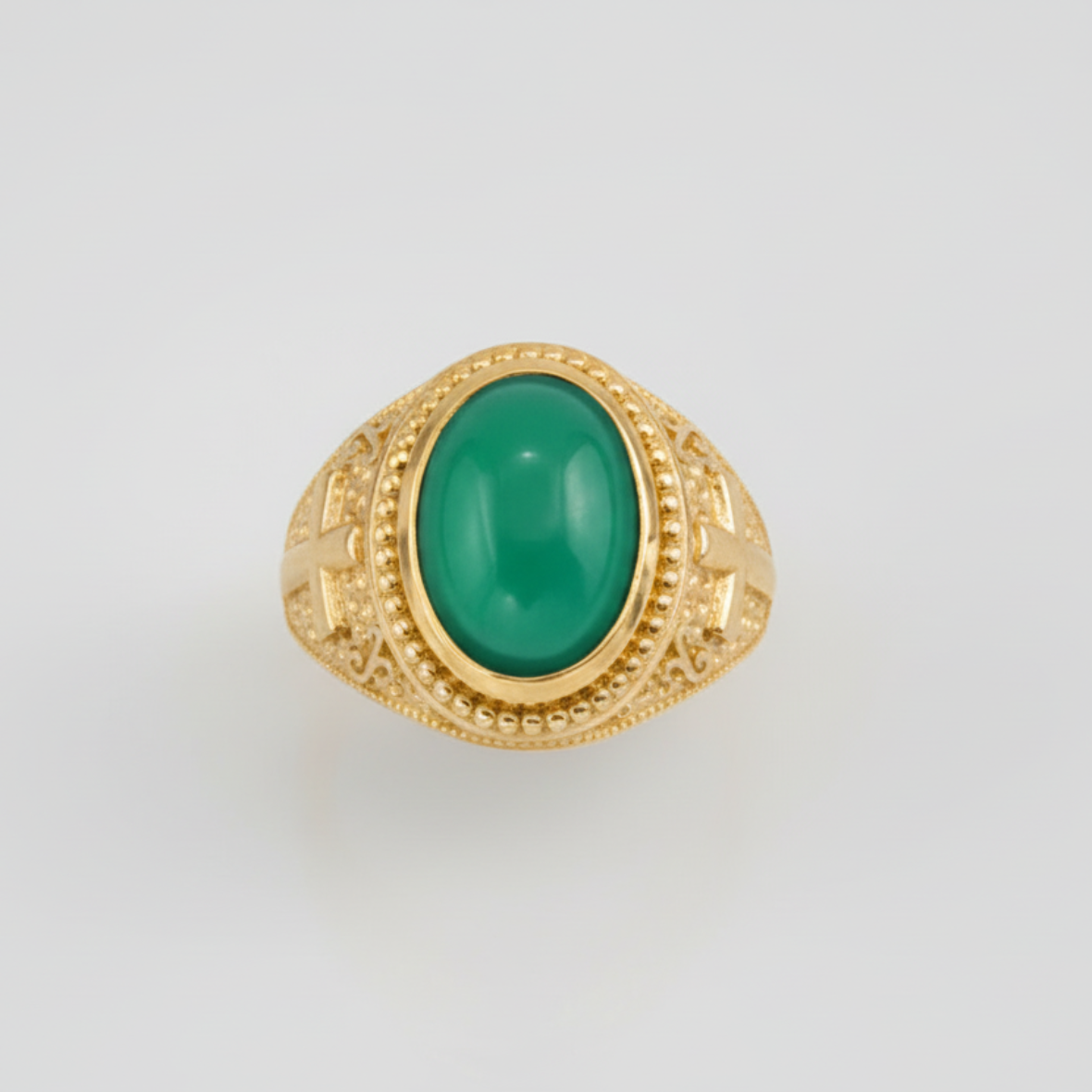 Gold ring with a green gemstone on a light gray background