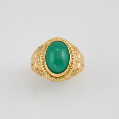 Gold ring with a green gemstone on a light gray background