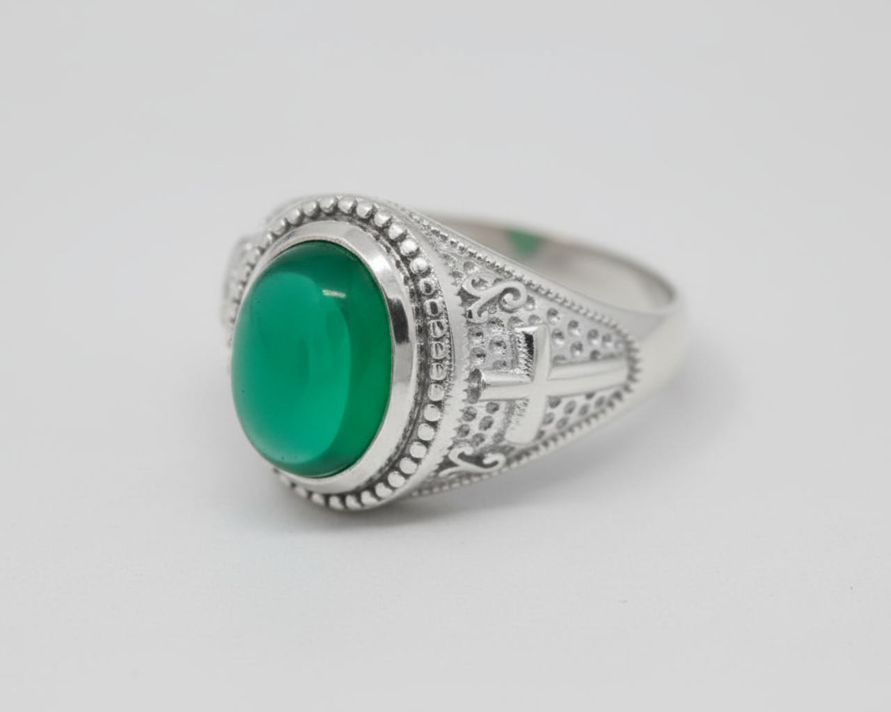 Silver ring with a green stone on a light gray background