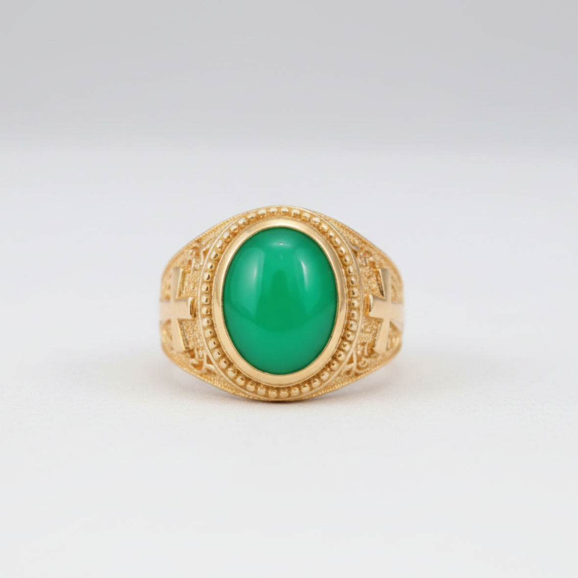 Gold ring with a green gemstone on a white background