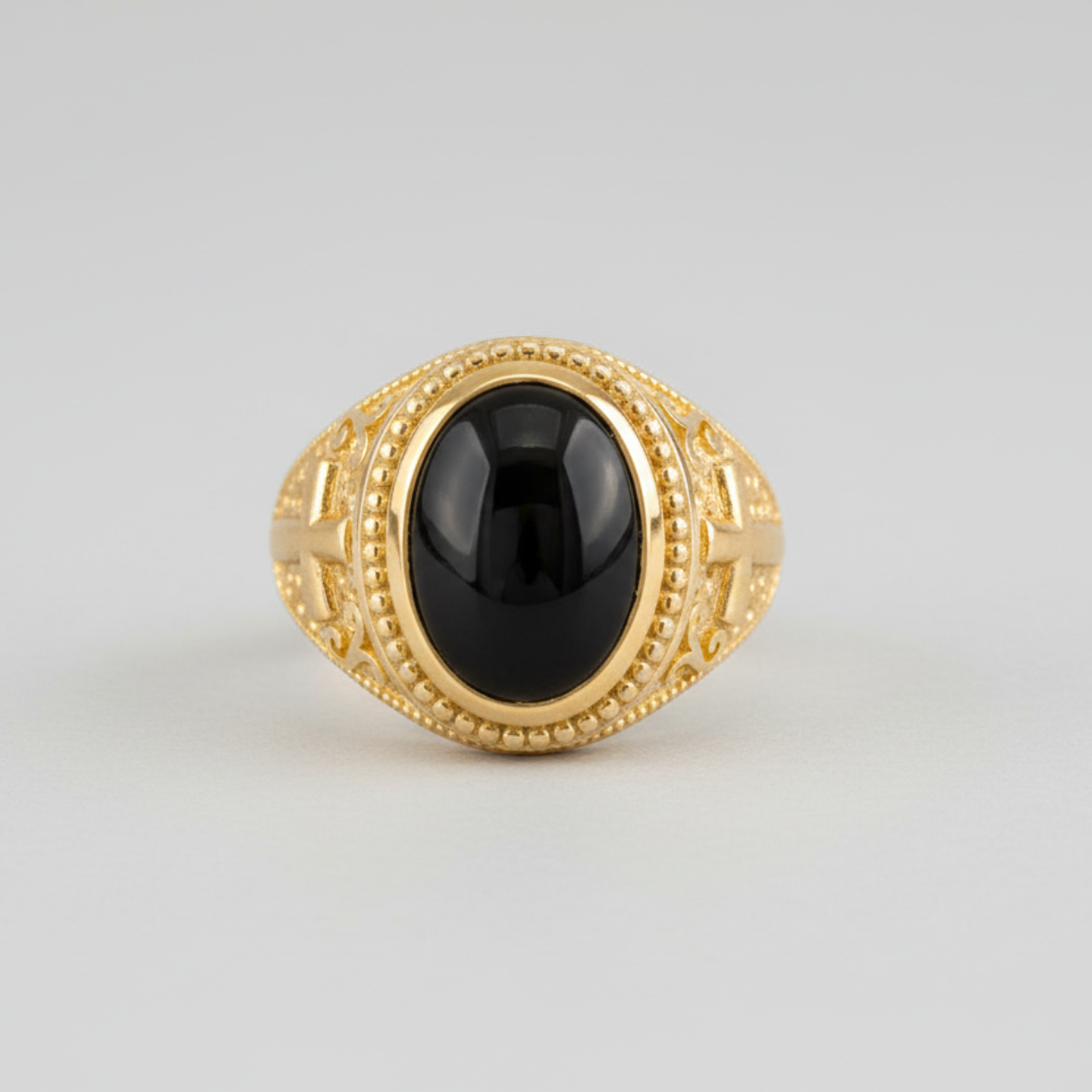 Gold ring with a black gemstone on a light gray background
