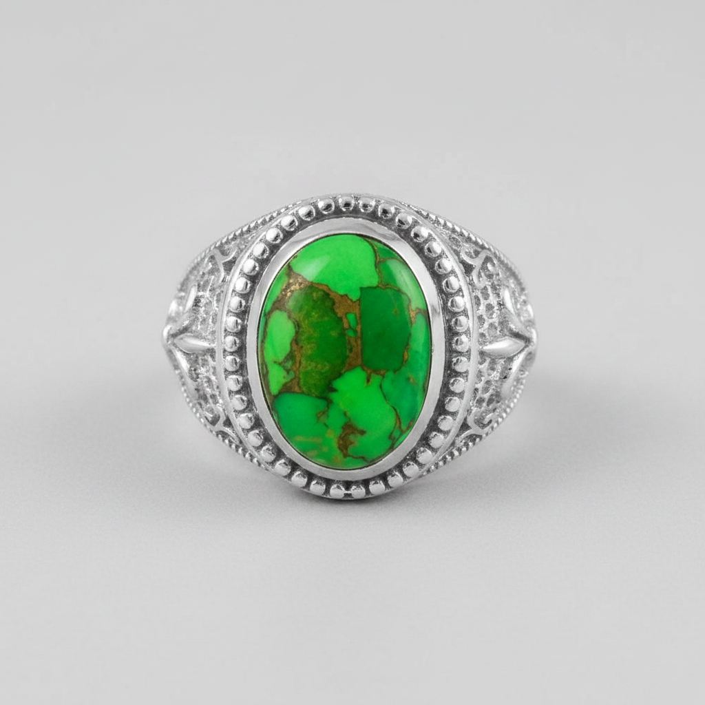 A silver ring featuring an oval green turquoise stone with natural brown matrix patterns, set in an ornate filigree-style silver band on a light gray background.