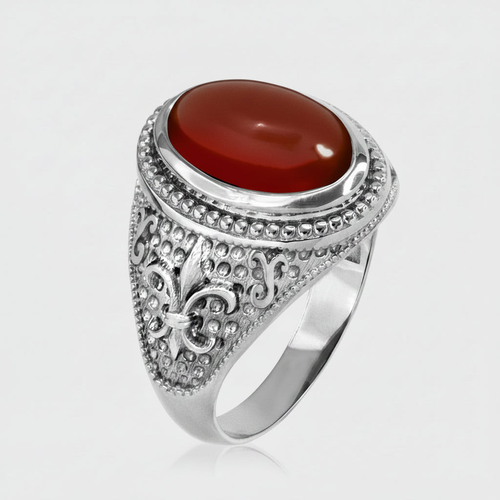 A silver-toned signet ring featuring a large, polished oval red cabochon gemstone, with an ornate filigree design on the band, set against a light gray background.