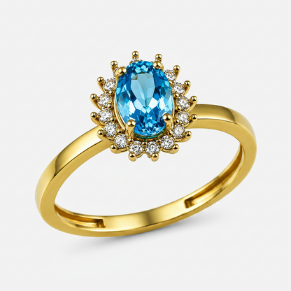 A yellow gold ring featuring a large oval-cut light blue gemstone in the center, surrounded by a halo of small clear stones, set on a polished gold band against a white background.