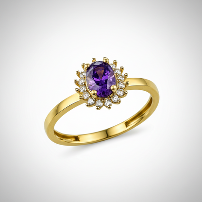 A yellow gold ring featuring an oval-cut purple amethyst center stone surrounded by a halo of small clear cubic zirconia stones, set on a polished gold band against a white background.