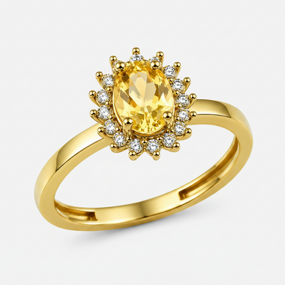 A yellow gold ring featuring a large oval-cut yellow gemstone surrounded by a halo of small clear stones, set on a polished yellow gold band against a white background.