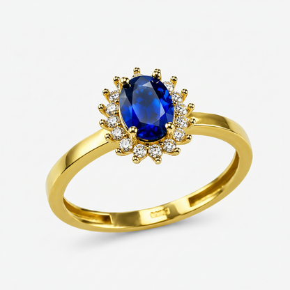 A yellow gold ring featuring a central oval-cut deep blue sapphire surrounded by a halo of small round-cut clear stones, set on a polished gold band against a white background.