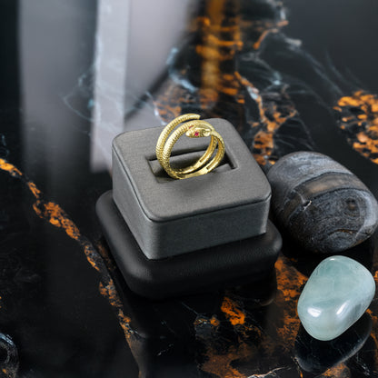 Textured yellow gold coiled snake wrap ring with ruby eyes, available in 10K/14K, on a gray display.