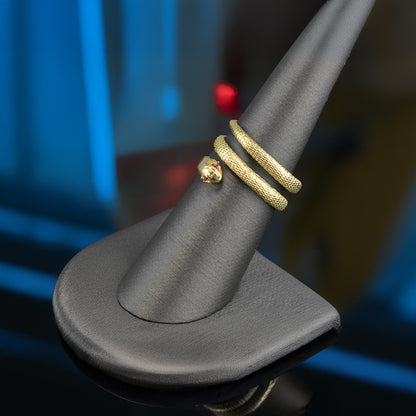 Textured yellow gold coiled snake wrap ring with ruby eyes and two textured bands on a display stand.