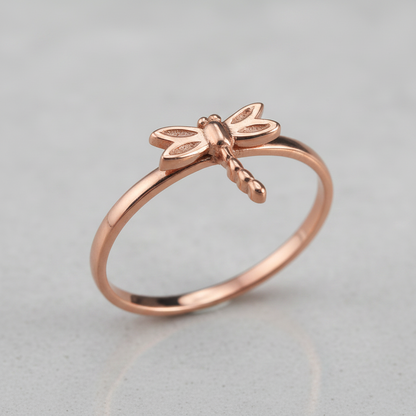Rose gold dragonfly ring on a light gray background